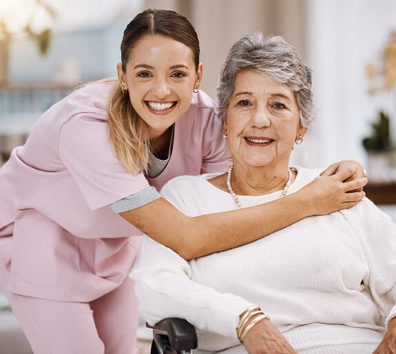 A smiling support worker embracing an older woman